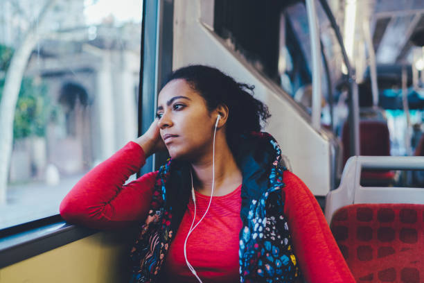 A woman is resting on a bus in the day time to stay warm and hidden from danger